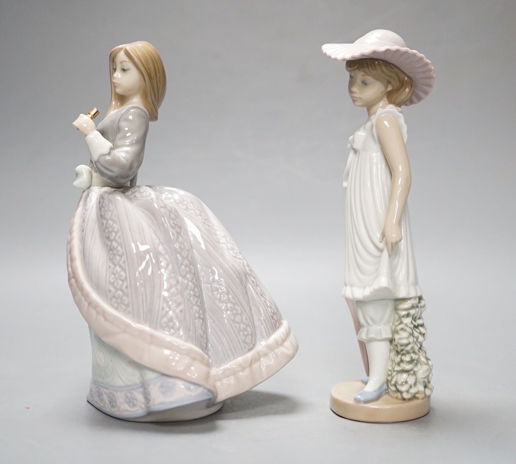 A Lladro figure of a lady with parasol, 18.5cm and a similar Nao figure